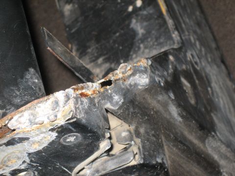 1995 Ford Bronco - Detail of a heavily rusted metal frame, showing signs of wear and corrosion.
