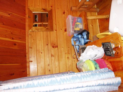 1978 Ford Bronco - A cluttered wooden room contains various stored items, including a toy and straps, with a small square window on the wall.