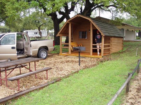 1978 Ford Bronco - A gold pickup truck is parked next to a picnic table and a small cabin.