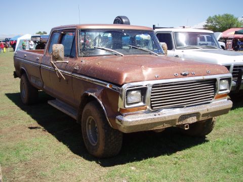 1978 Ford Bronco - This brown 1978 Ford F-Series pickup truck is seen in a 3/4 front view, with another white truck behind it.