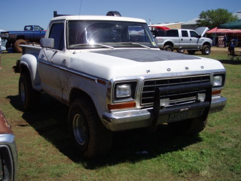 1978 Ford Bronco - A white 1978 Ford F-150 pickup truck is parked on grass, with other vehicles in the background.