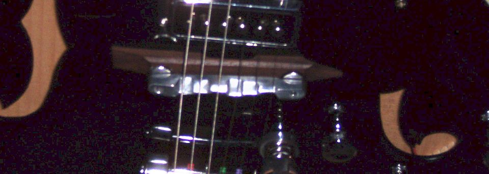 Dark blurry close-up of an electric guitar bridge and strings