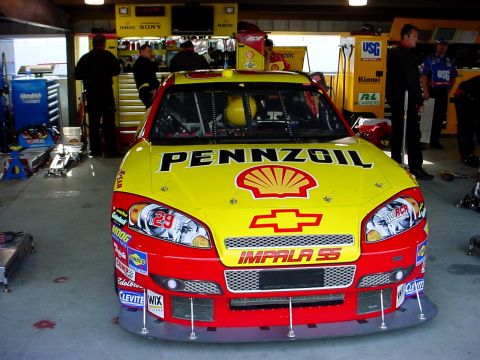 1993 Ford Mustang - A race car with Pennzoil sponsorship is parked in a garage, displaying its front end and various sponsor decals.