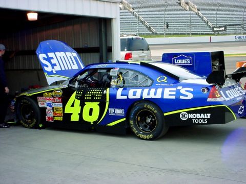 1993 Ford Mustang - A race car with 'Lowe's' branding is parked in a garage with its hood open.
