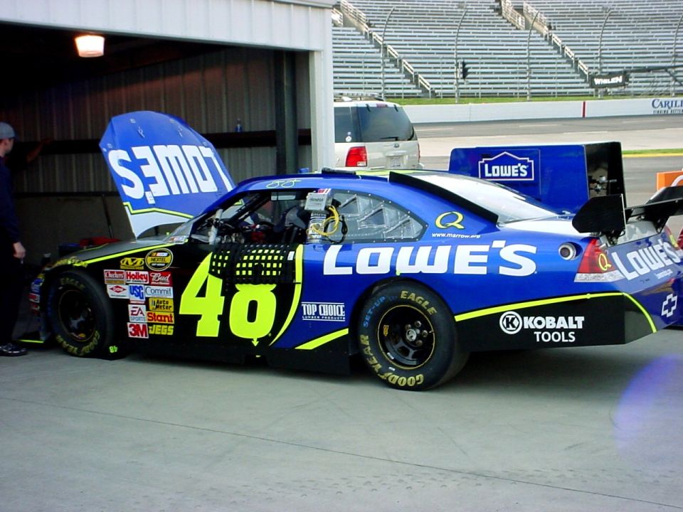Blue and yellow race car with number 40, hood open, parked in a garage