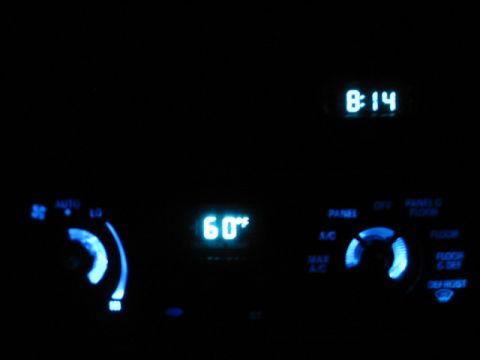 1995 Ford Thunderbird - The illuminated climate controls and clock display glow blue in the dark interior of a vehicle.
