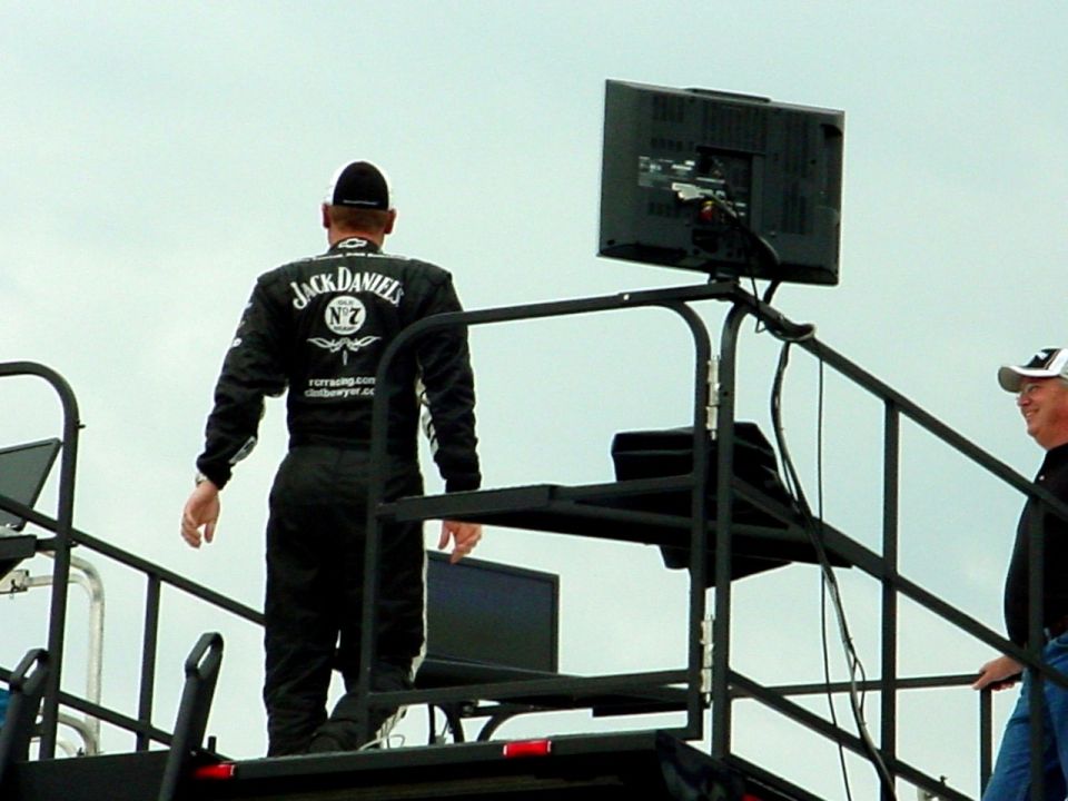 Person in a black Jack Daniel's firesuit standing on a pit box with a monitor