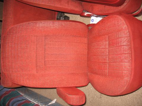1990 Ford Bronco - Close-up of red patterned car seats and a center armrest.