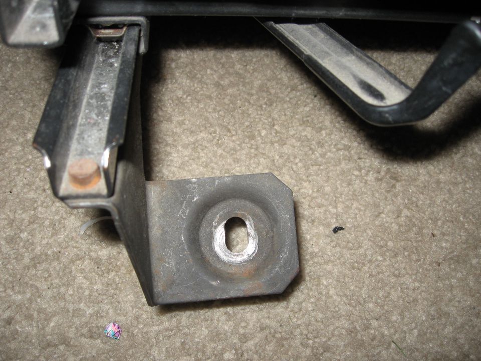 metal bracket with a hole in it, sitting on carpet. Supermotors.net logo in corner