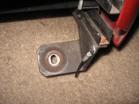 1990 Ford Bronco - Close-up of a metal bracket with a cable, likely a vehicle part, on a carpeted surface.