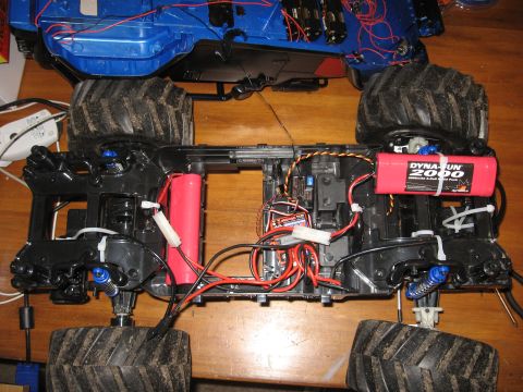 1990 Ford Bronco - The underside of a remote-controlled monster truck is shown, revealing its internal components and wiring.