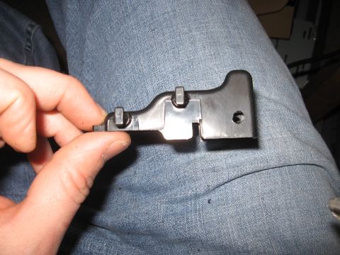 1990 Ford Bronco - A person holds a black plastic automotive part with metal screws.