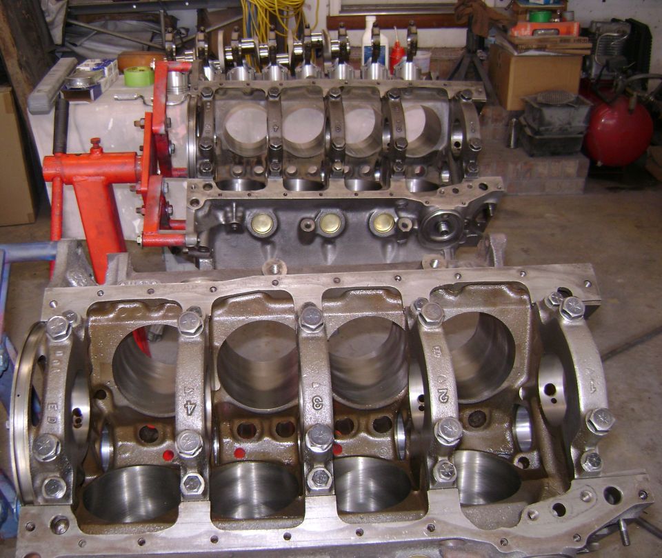 Two disassembled V8 engine blocks with numbered main caps in a garage