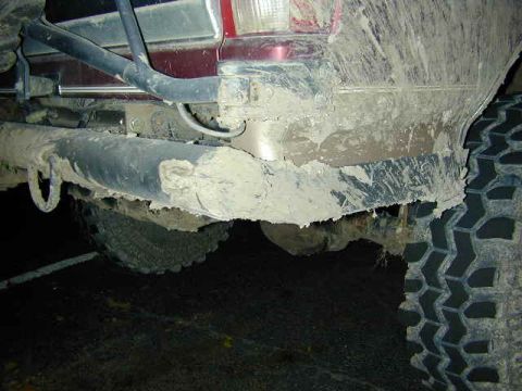 1996 Ford Bronco - The rear bumper and tire of a vehicle are heavily covered in mud, obscuring details.