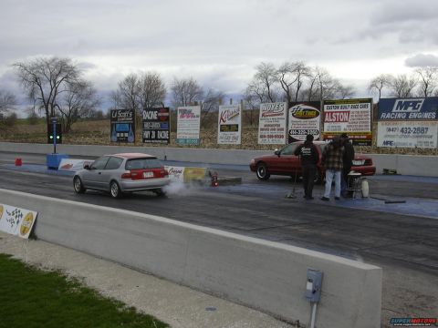 1998 Ford Crown Victoria - A red 1998 Ford Crown Victoria sits on the drag strip with crew members nearby.