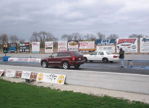 1998 Ford Crown Victoria - A drag race is about to begin with an SUV and a sedan lined up on the track.