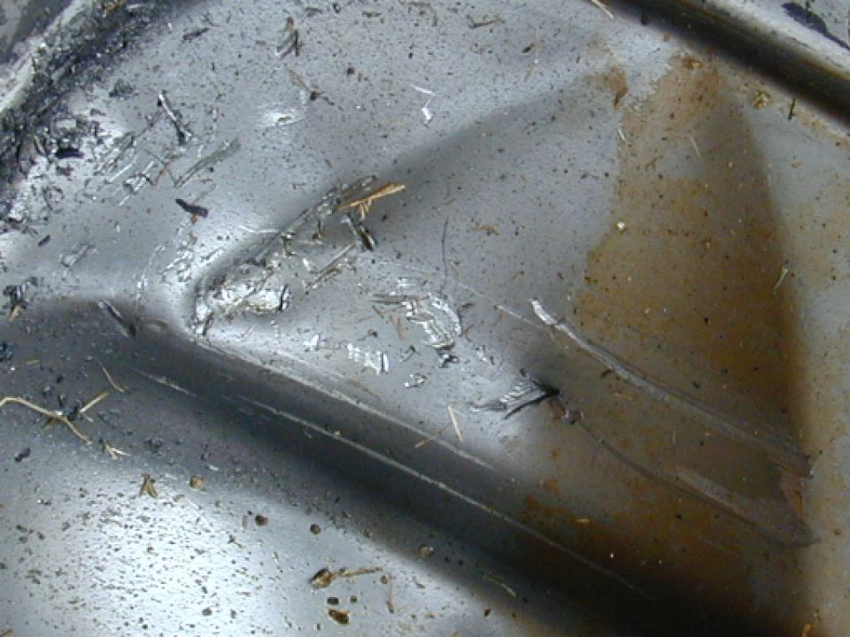 Steel differential cover torn open from inside with embedded metal shards and dented sheet metal