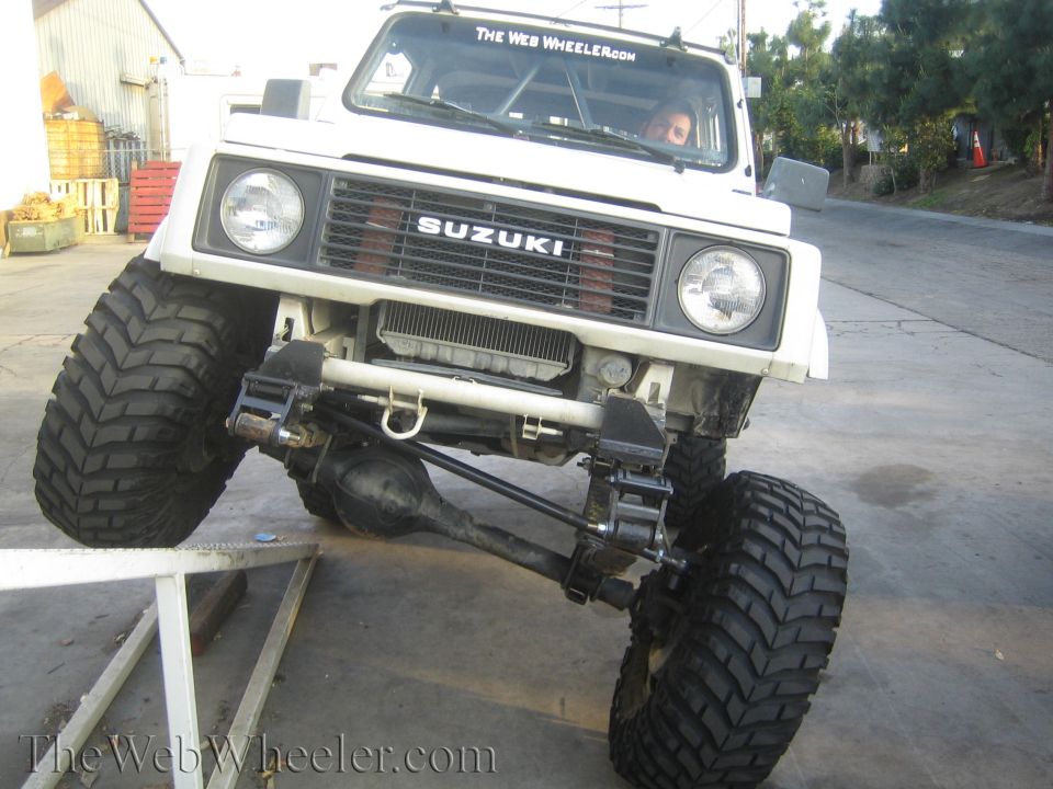 White lifted Suzuki Samurai front view showing solid axle and big off-road tires