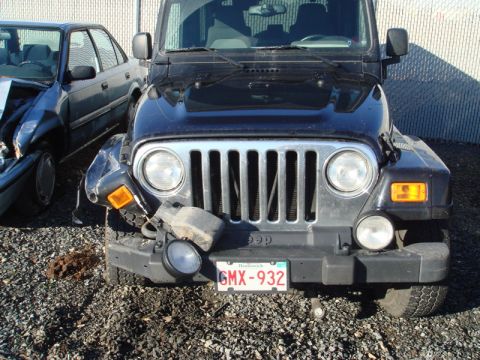 1996 Ford Bronco - A black Jeep Wrangler shows damage to its front end, parked beside another damaged vehicle.