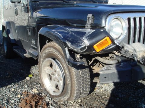 1996 Ford Bronco - This Jeep Wrangler has significant damage to its front passenger side fender and a flat tire.