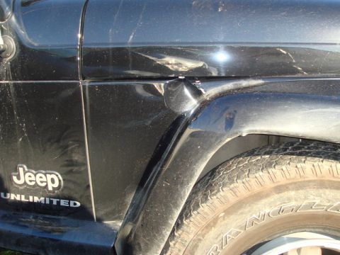 1996 Ford Bronco - Close-up of a black Jeep Wrangler Unlimited showing damage to the body panels and fender.