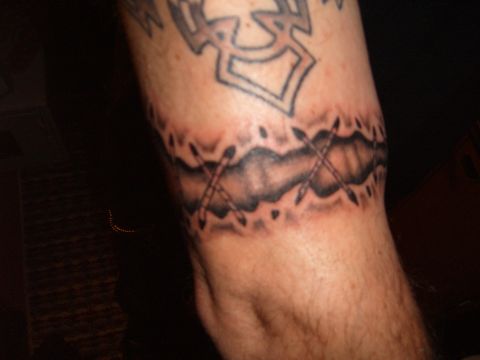 1993 Ford Bronco - A tattoo band encircles the arm, a jagged line with crossed arrows and tribal elements above.