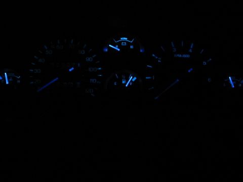 1995 Ford Thunderbird - The illuminated dashboard gauges glow blue in the dark, showing speed, RPM, fuel, and temperature readings.