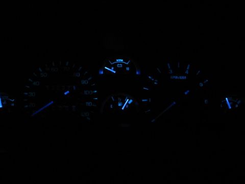 1995 Ford Thunderbird - A car's instrument cluster displays blue illuminated gauges in the dark.