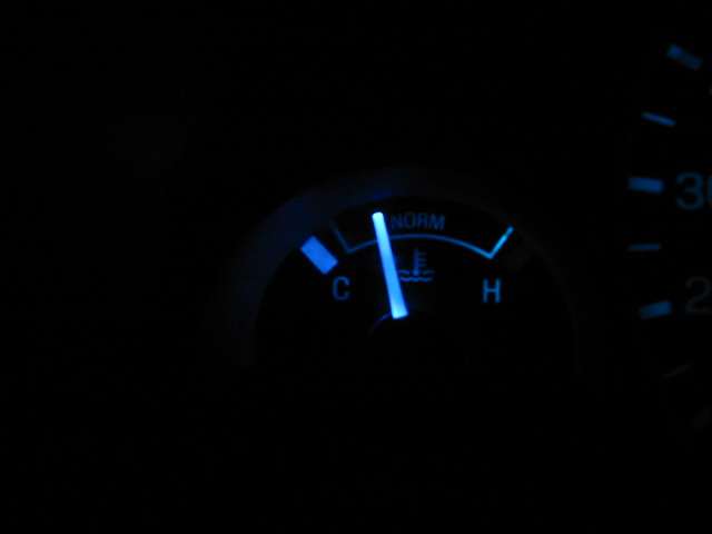 Blue illuminated temperature gauge with needle pointing to 'C'