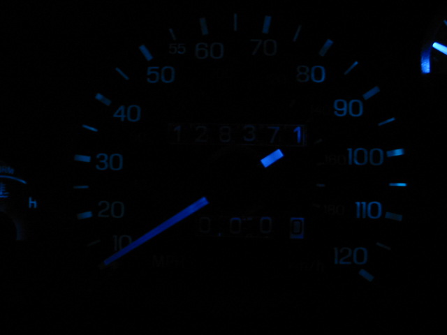 Car dashboard with blue illuminated speedometer and odometer. Odometer reads 128371