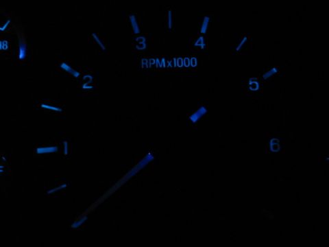 1995 Ford Thunderbird - A close-up of a car's tachometer gauge displays RPMs with blue illumination.