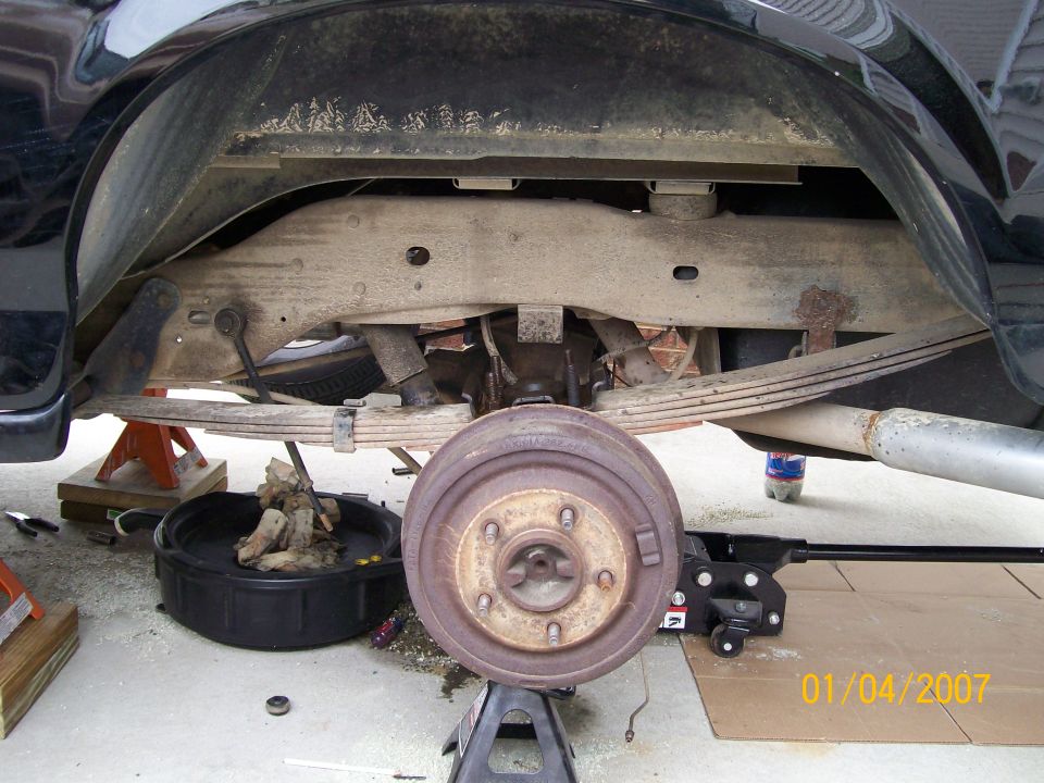 Black 1996 Ford Bronco rear axle and suspension with brake drum removed