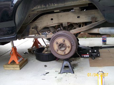 1996 Ford Bronco - Rear suspension and axle components of a vehicle are supported by jack stands during maintenance.