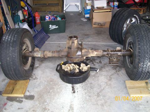 1996 Ford Bronco - A rear axle assembly with tires is shown in a garage setting, with a drain pan underneath.