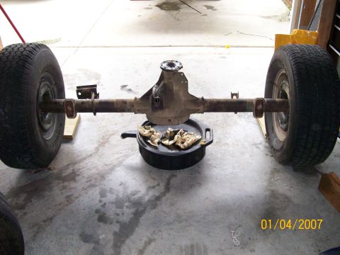 1996 Ford Bronco - Rear axle assembly with wheels and an oil drain pan underneath.