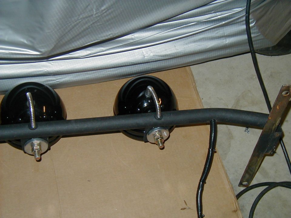 lightbar with two black spotlights mounted on a curved bar, with wiring and a metal bracket attached