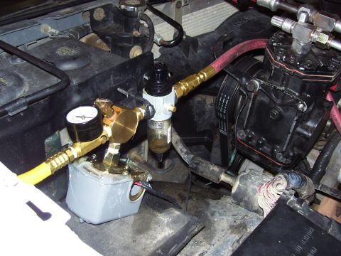 1992 Ford Bronco - Close-up view of an engine compartment showing an air compressor and associated plumbing.