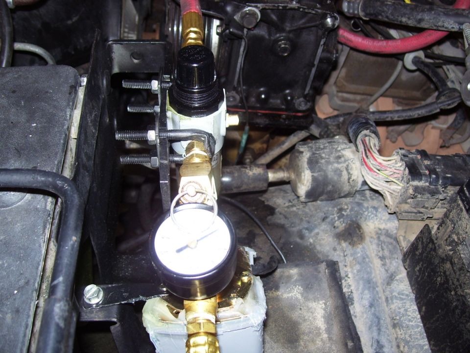 On-board air regulator and pressure gauge with brass fittings mounted in an engine bay