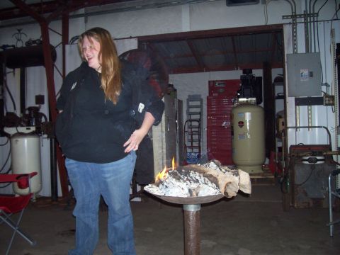1989 Ford Bronco II - A woman smiles while standing next to a burning fire pit inside a workshop or garage.