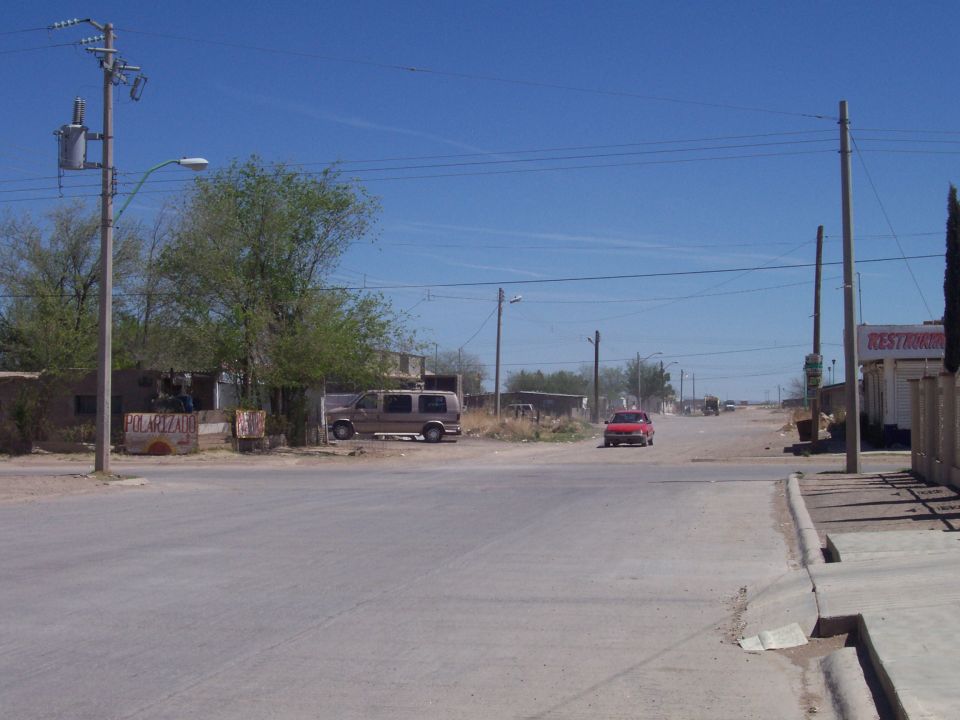 Dusty desert street corner with a parked van and a red car