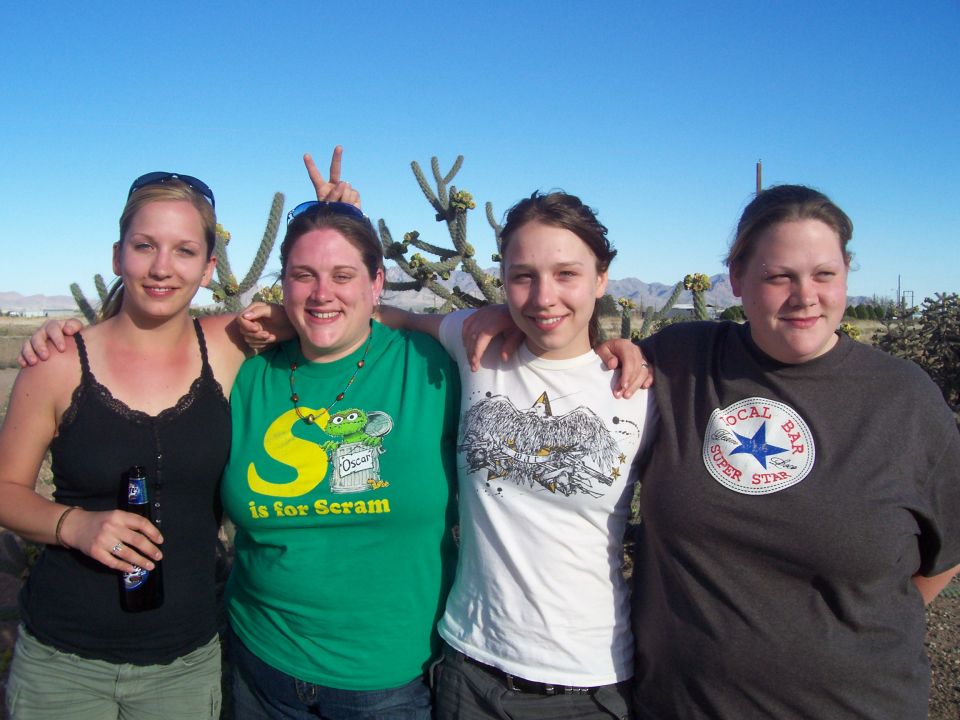 Close group of four women, one making bunny ears, in the desert