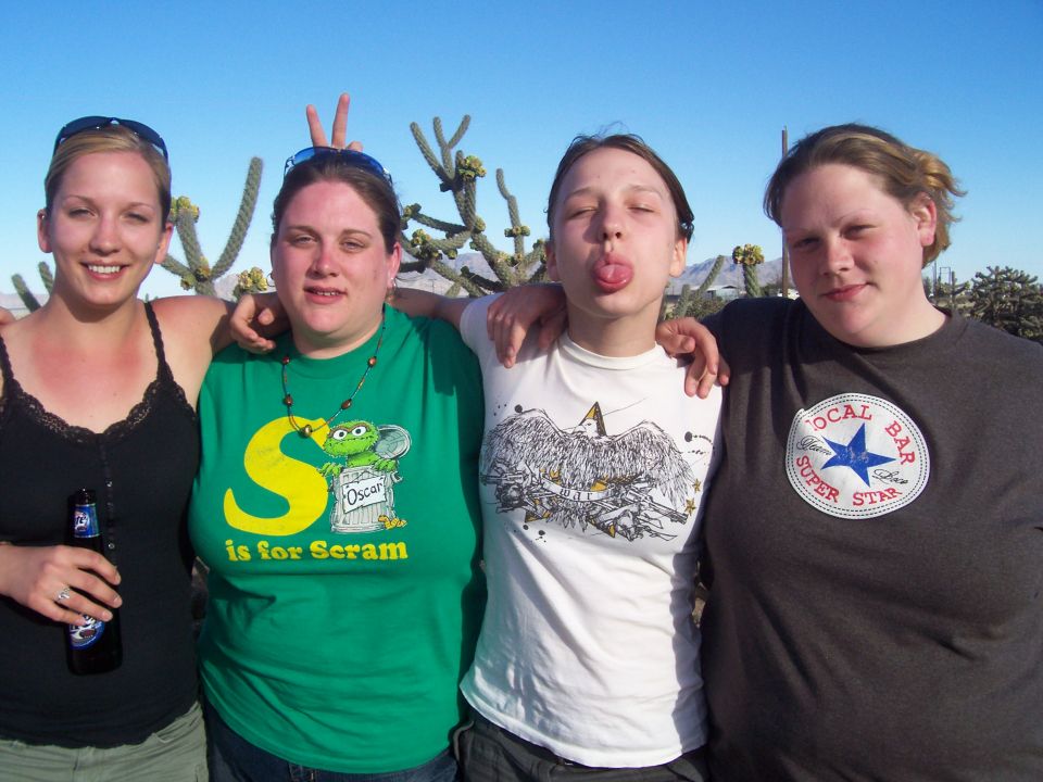 Four women being playful, one sticking out tongue, in the desert