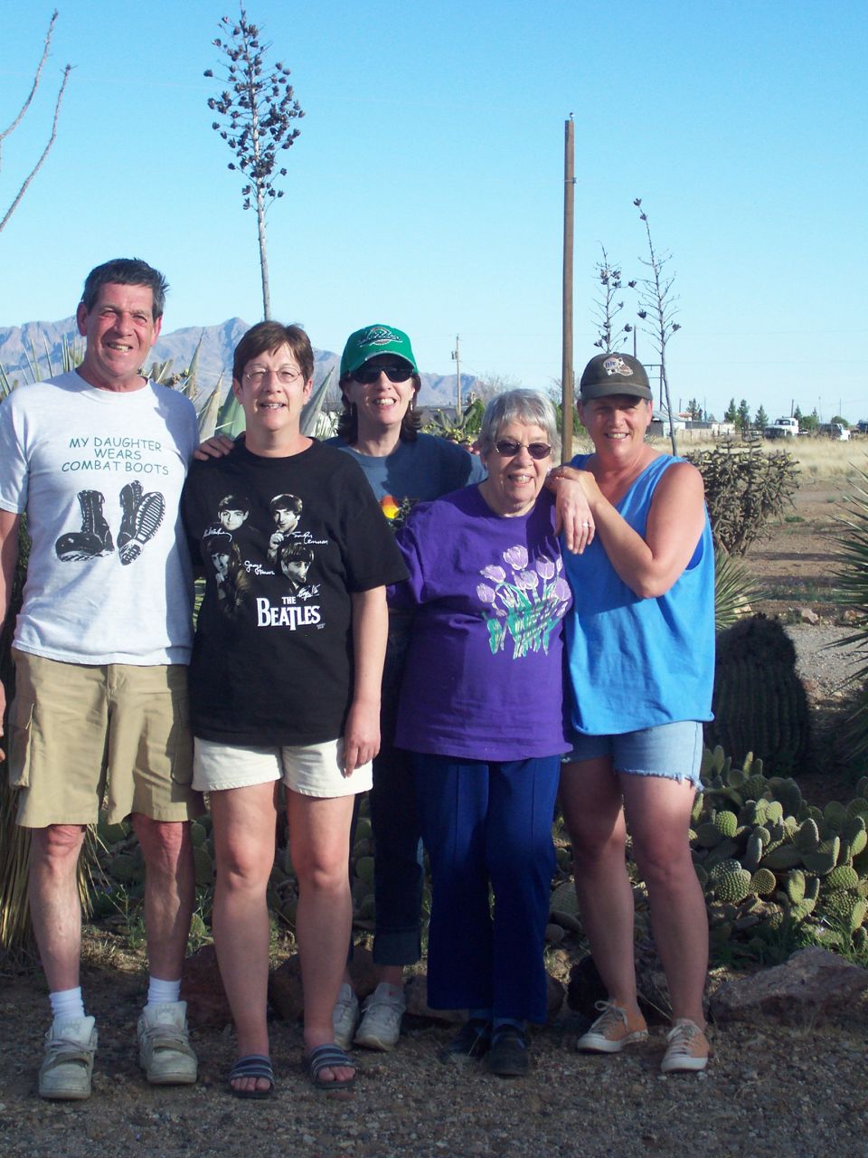 Group of five people posing in a desert yard, vertical framing