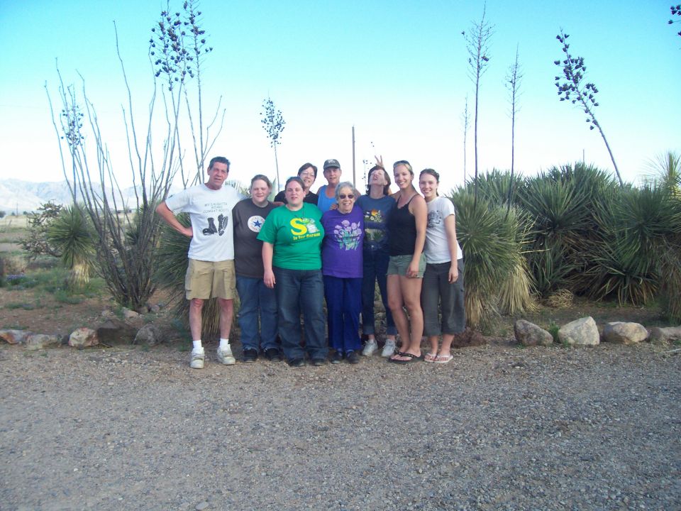 Large group of about nine people posing in a desert landscape
