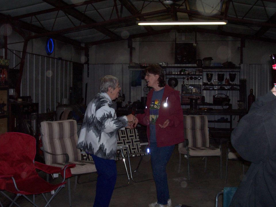 Two older women shaking hands inside a metal pole barn shop