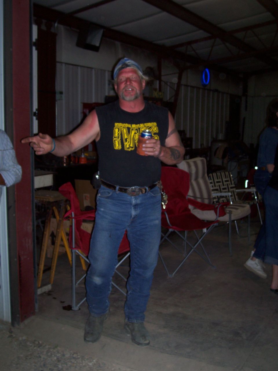 Man in IWF wrestling shirt and bandana holding a drink in a shop