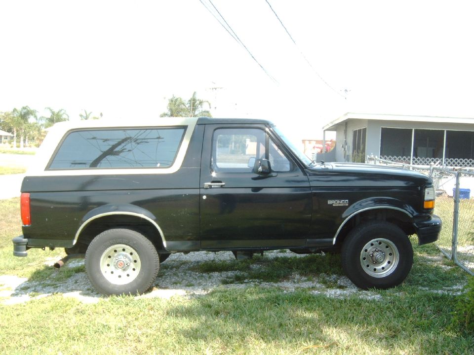 Side view of a black 1994 Ford Bronco with a tan top parked on grass