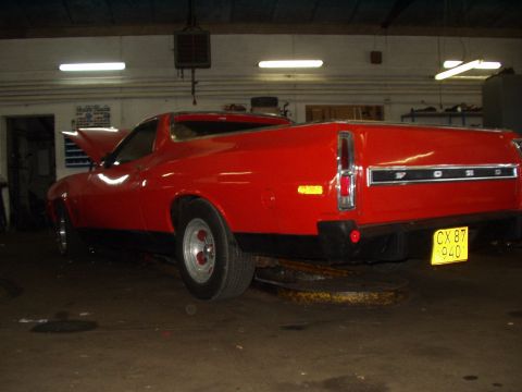 1974 Ford Ranchero - Rear view of a red 1974 Ford Ranchero in a garage, showing its distinctive tailgate and taillights.