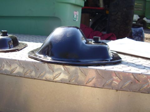 1981 Jeep CJ7 - A black metal automotive part sits on a diamond plate surface, with a green container and tire in the background.