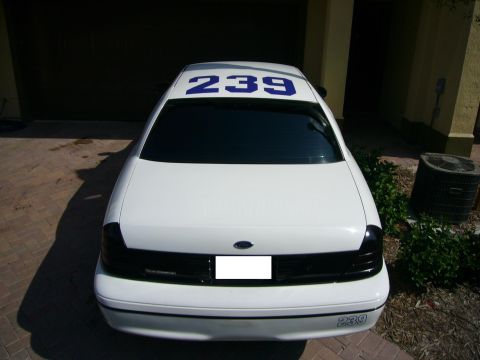2000 Ford Crown Victoria - White 2000 Ford Crown Victoria, rear view, showing blue numbers '239' on roof and trunk.